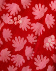 Close up display of red dress with pink flowers, fabric.