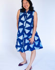 Model wearing blue sleeveless dress with white triangle print.