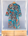 Display of beige, orange, navy and aqua, abstract print dress.