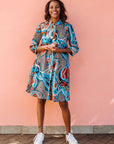 Model wearing beige, orange, navy and aqua, abstract print dress.