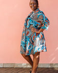 Model wearing beige, orange, navy and aqua, abstract print dress.