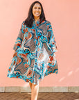 Model wearing beige, orange, navy and aqua, abstract print dress.