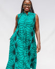 A person wearing a sleeveless, teal blue and black geometric patterned dress.