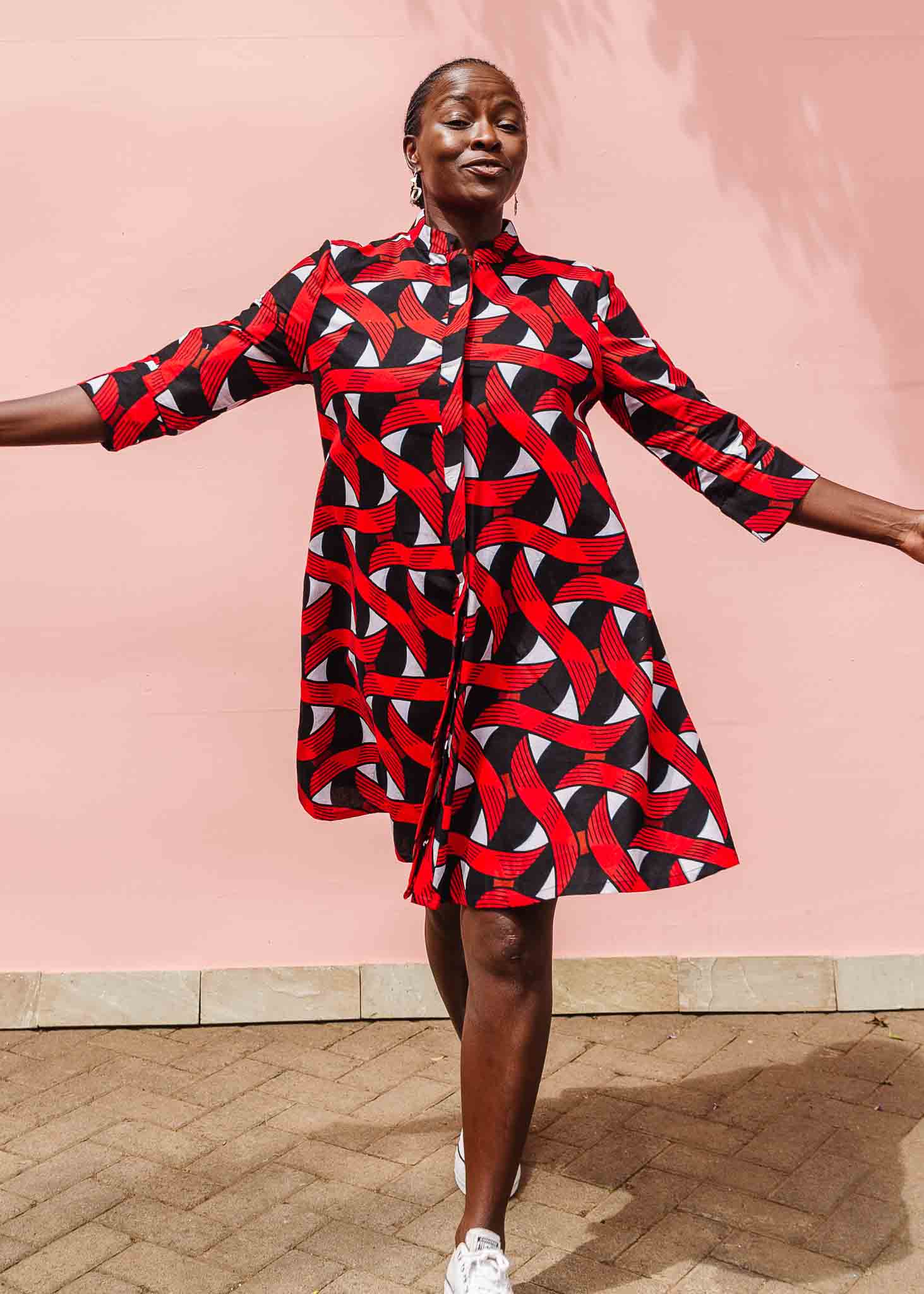 Model wearing red, black and white ribbon print dress.