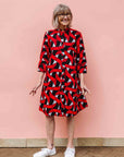 Model wearing red, black and white ribbon print dress.