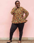 Model wearing mustard long sleeve blouse with red floral print.