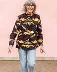 Model wearing long sleeve blouse with brown and yellow abstract print.