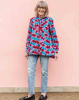 Model wearing pink, red, blue and black tube print long sleeve blouse.