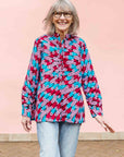 Model wearing pink, red, blue and black tube print long sleeve blouse.