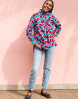 Model wearing pink, red, blue and black tube print long sleeve blouse.