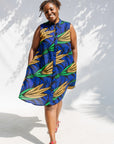 Model wearing blue sleeveless dress with orange and green print.