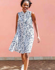 Model wearing white sleeveless dress with blue floral print.