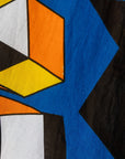 Close up display of blue dress with yellow, black, orange and white geometric print, fabric.