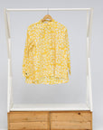 Display of yellow long sleeve shirt with white leaf print.