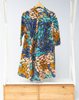 Display of black dress with yellow dots and brown, blues, peach leaves.