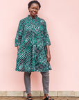 The model is wearing black, green and white geometric print dress