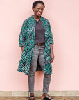 The model is wearing black, green and white geometric print dress