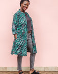 The model is wearing black, green and white geometric print dress