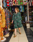 The model is wearing black, green and white geometric print dress