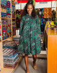 The model is wearing black, green and white geometric print dress