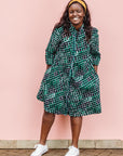 The model is wearing black, green and white geometric print dress