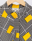 Display of black and white striped dress with yellow block print.
