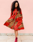 Model wearing red and brown abstract print dress.