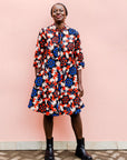 model wearing a colorful geometric shirt dress with a pinwheel design