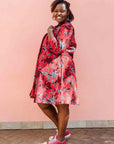 Model wearing red dress with floral vine print.