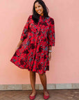 Model wearing red dress with floral vine print.