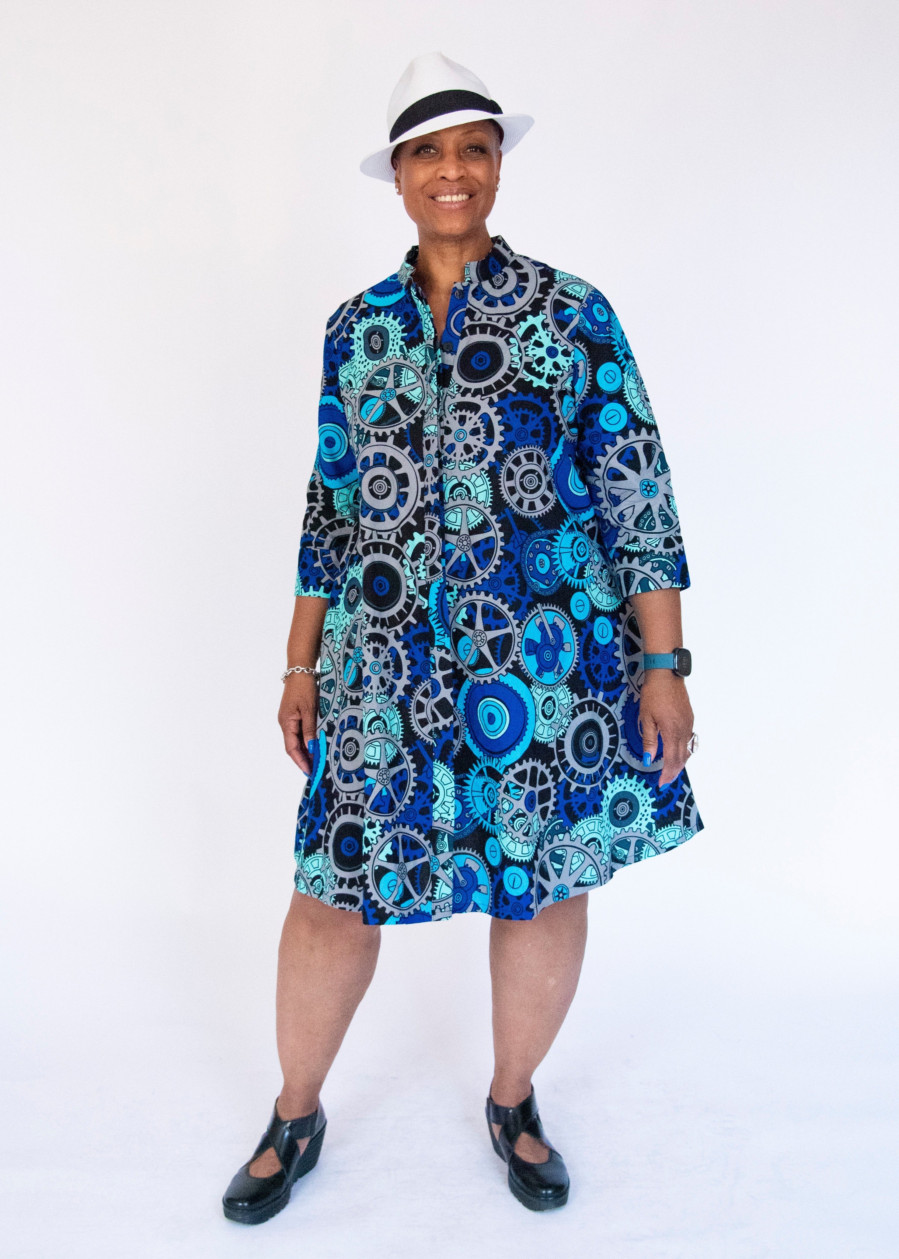 Model wearing dress with blue and grey gear graphic print.