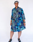 Model wearing dress with blue and grey gear graphic print.