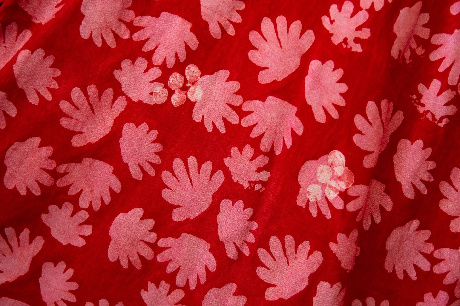 Close up display of red dress with pink flowers, fabric.