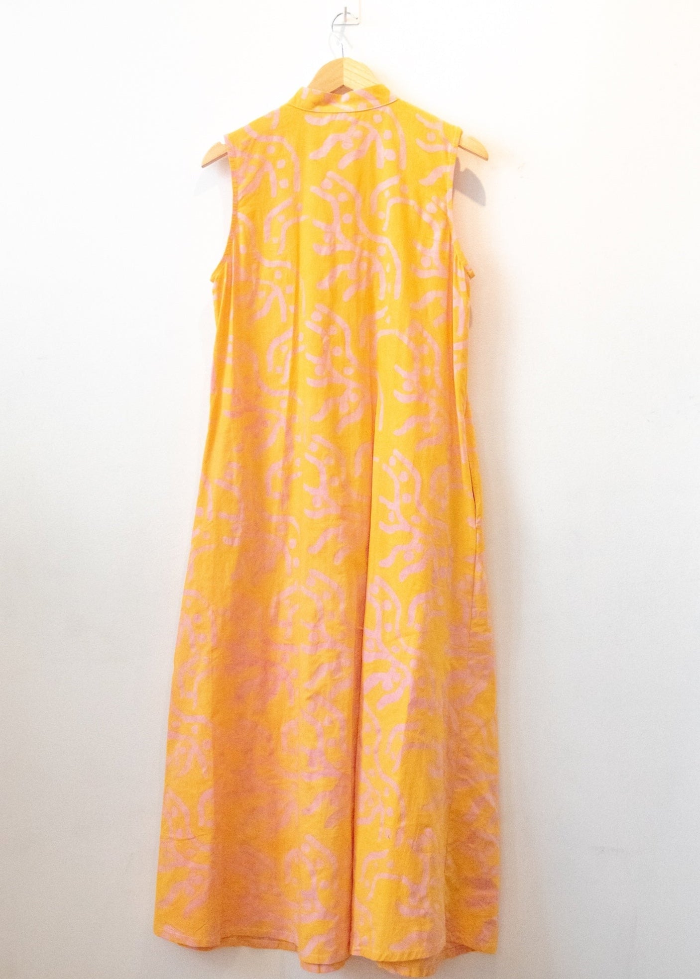 Display of yellow sleeveless dress with abstract pink print.