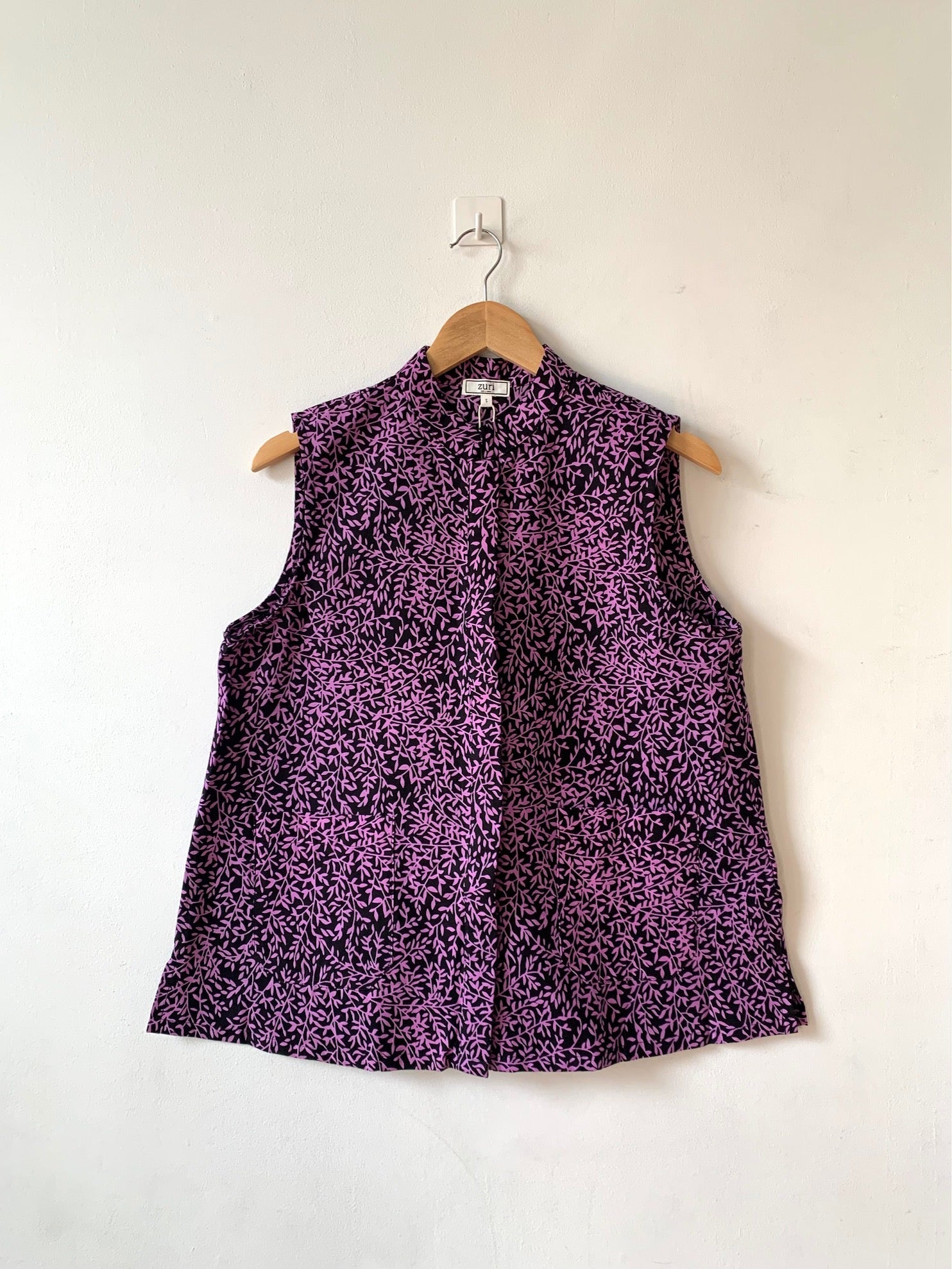 Display of black and purple floral print sleeveless shirt.