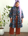 model wearing floral and leaf print navy dress open as a lightweight jacket over a shirt