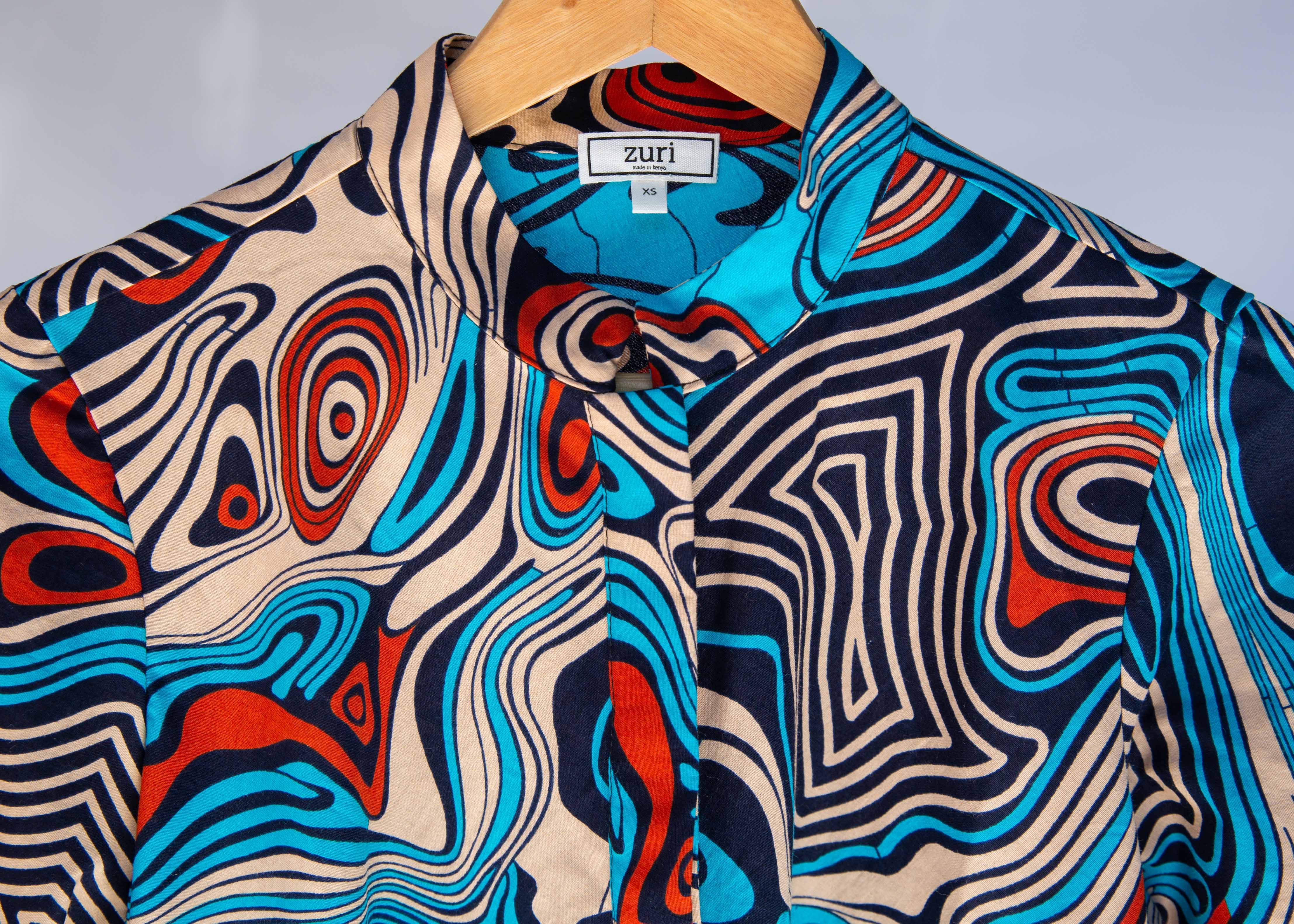 Display of beige, orange, navy and aqua, abstract print dress.