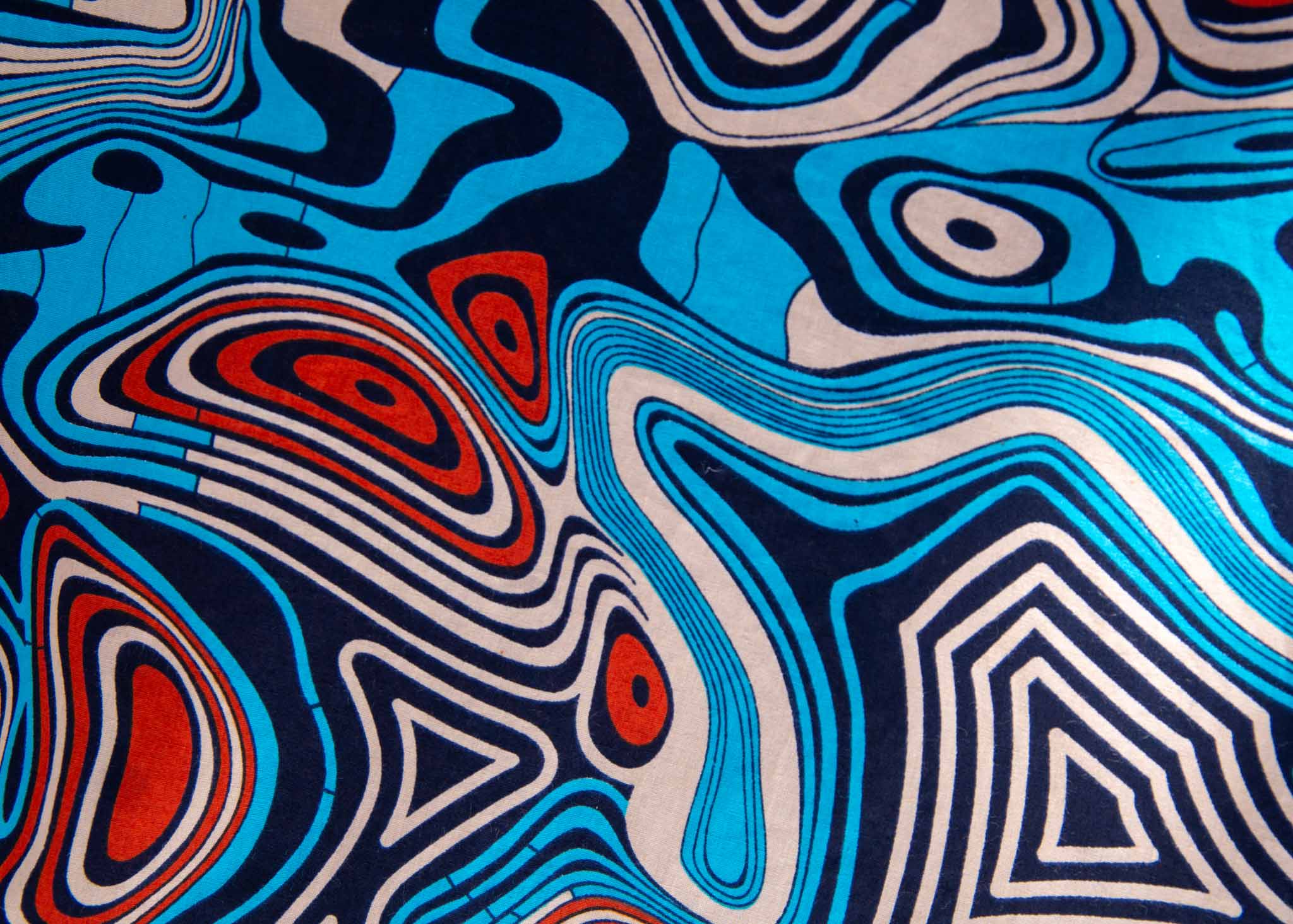Close up display of beige, orange, navy and aqua, abstract print dress, fabric.