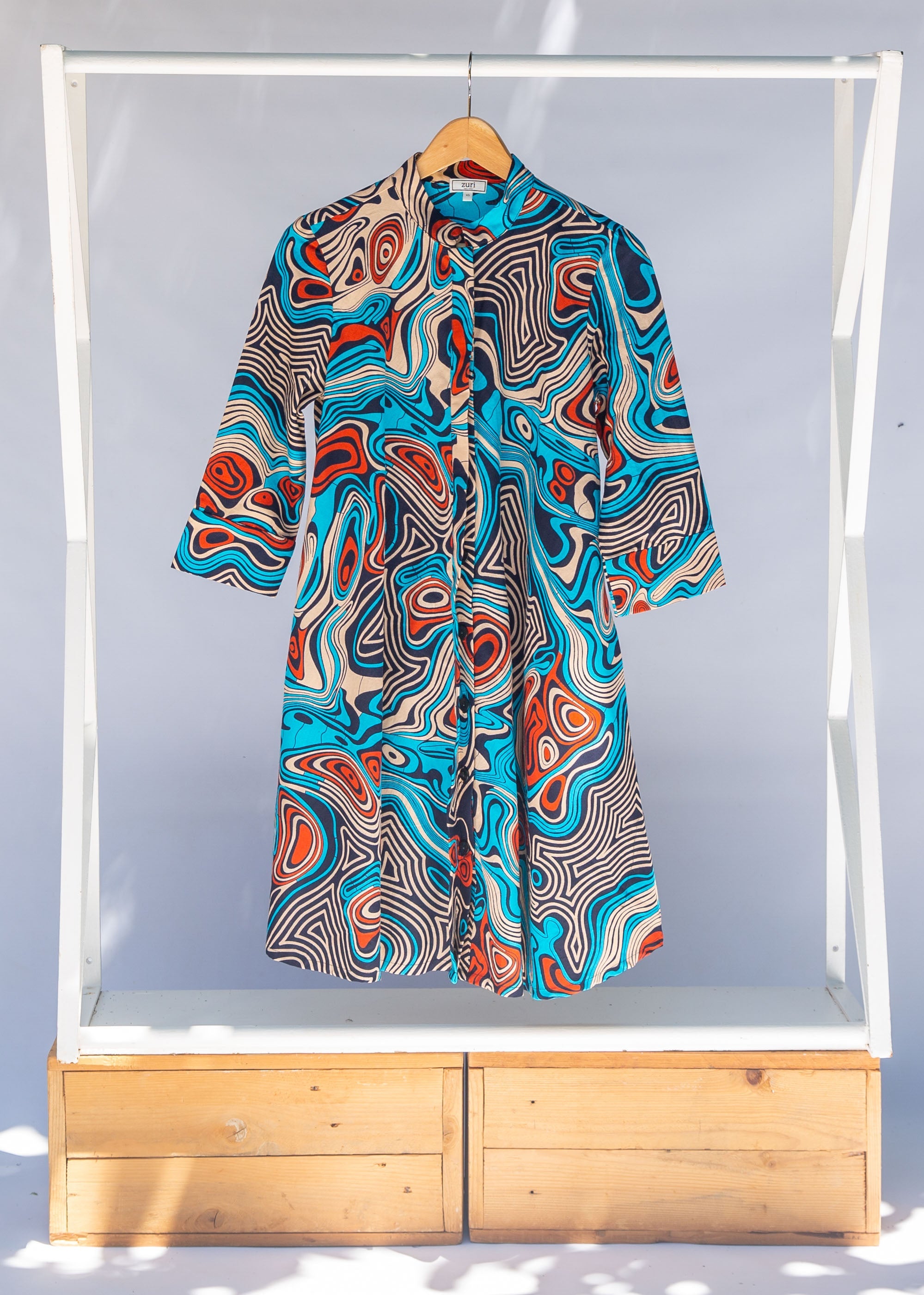 Display of beige, orange, navy and aqua, abstract print dress.