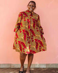Model wearing brown dress with red snap pea print.