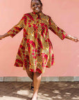 Model wearing brown dress with red snap pea print.
