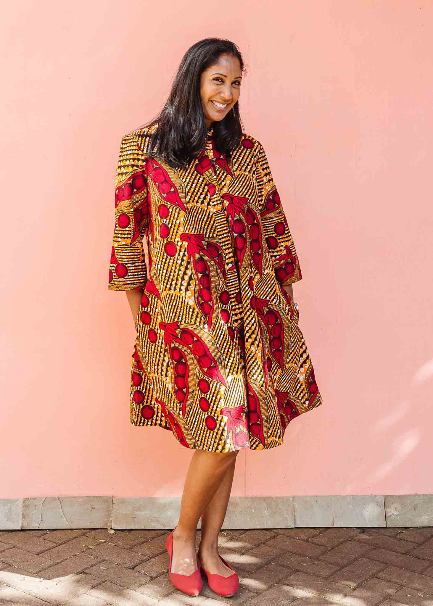 Model wearing brown dress with red snap pea print.