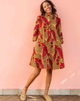 Model wearing brown dress with red snap pea print.