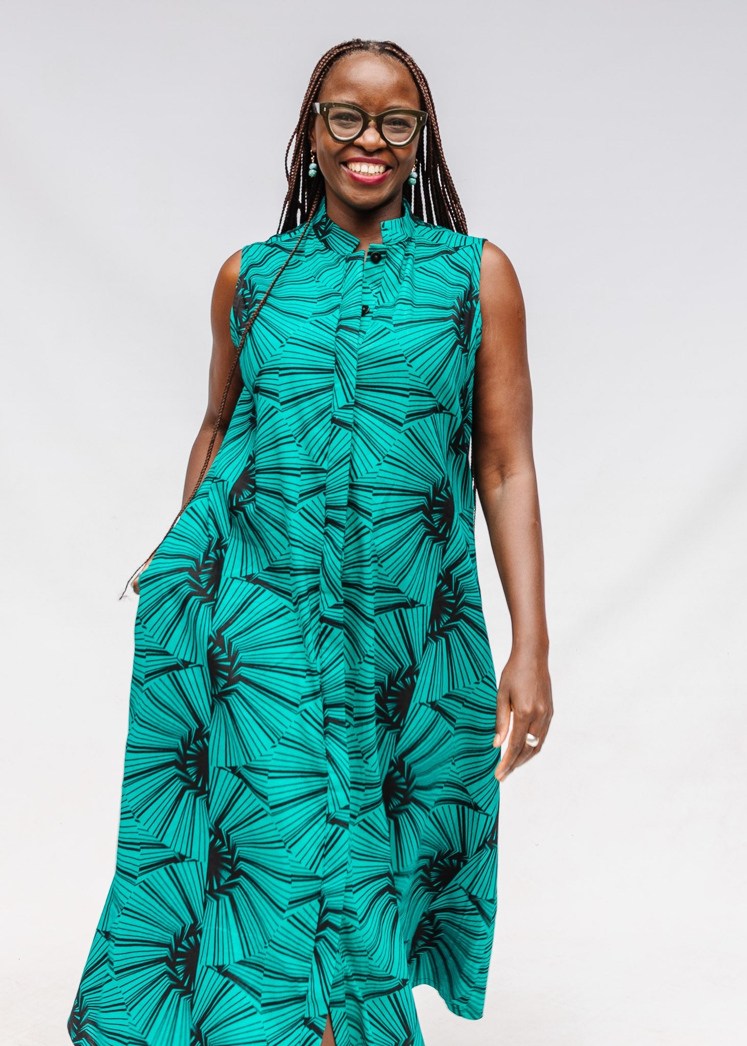 A person wearing a sleeveless, teal blue and black geometric patterned dress.