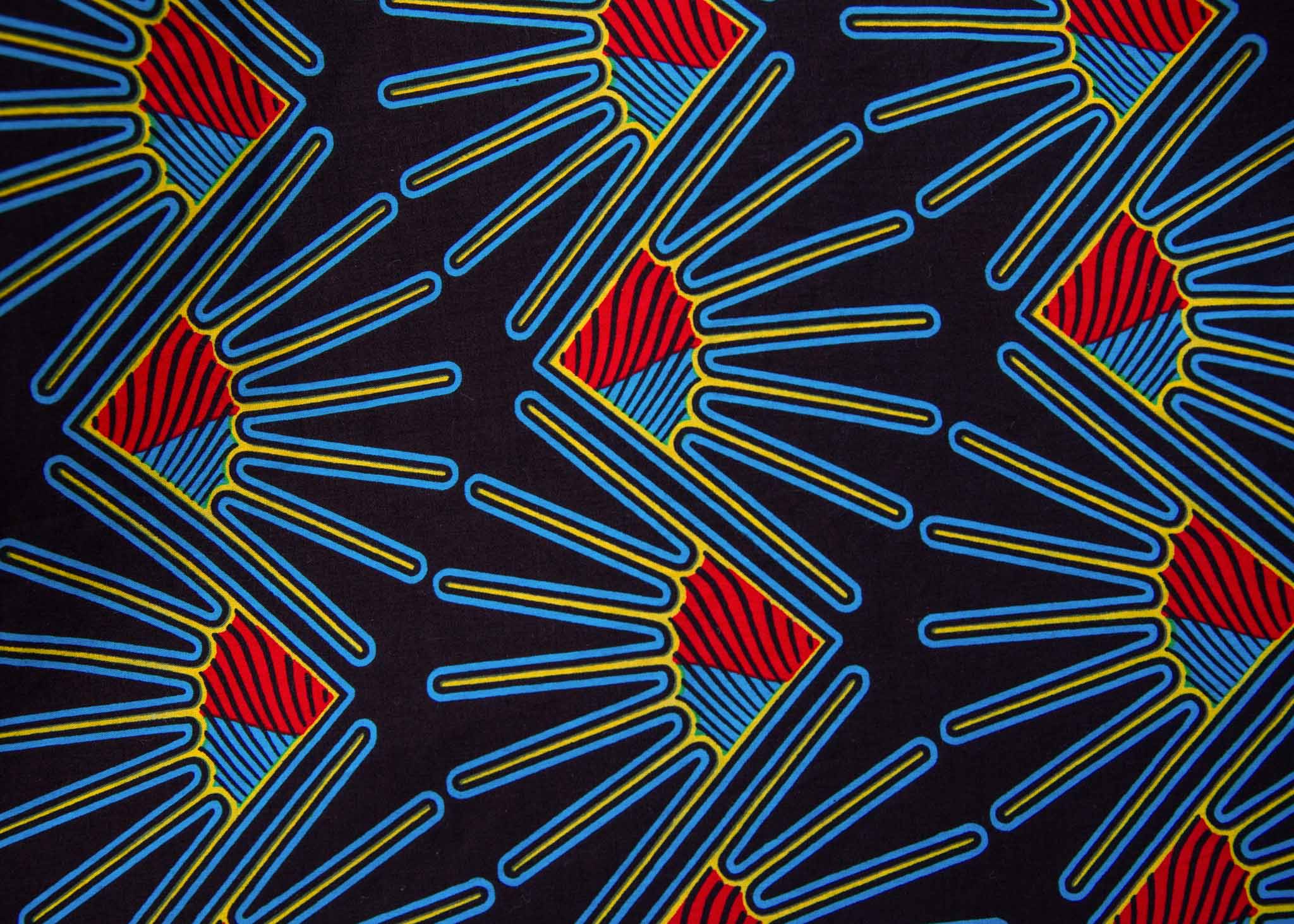 Close up display of black dress with blue, red and yellow fan design, fabric.