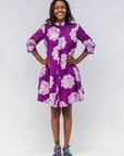 Woman wearing a purple floral dress against a white background