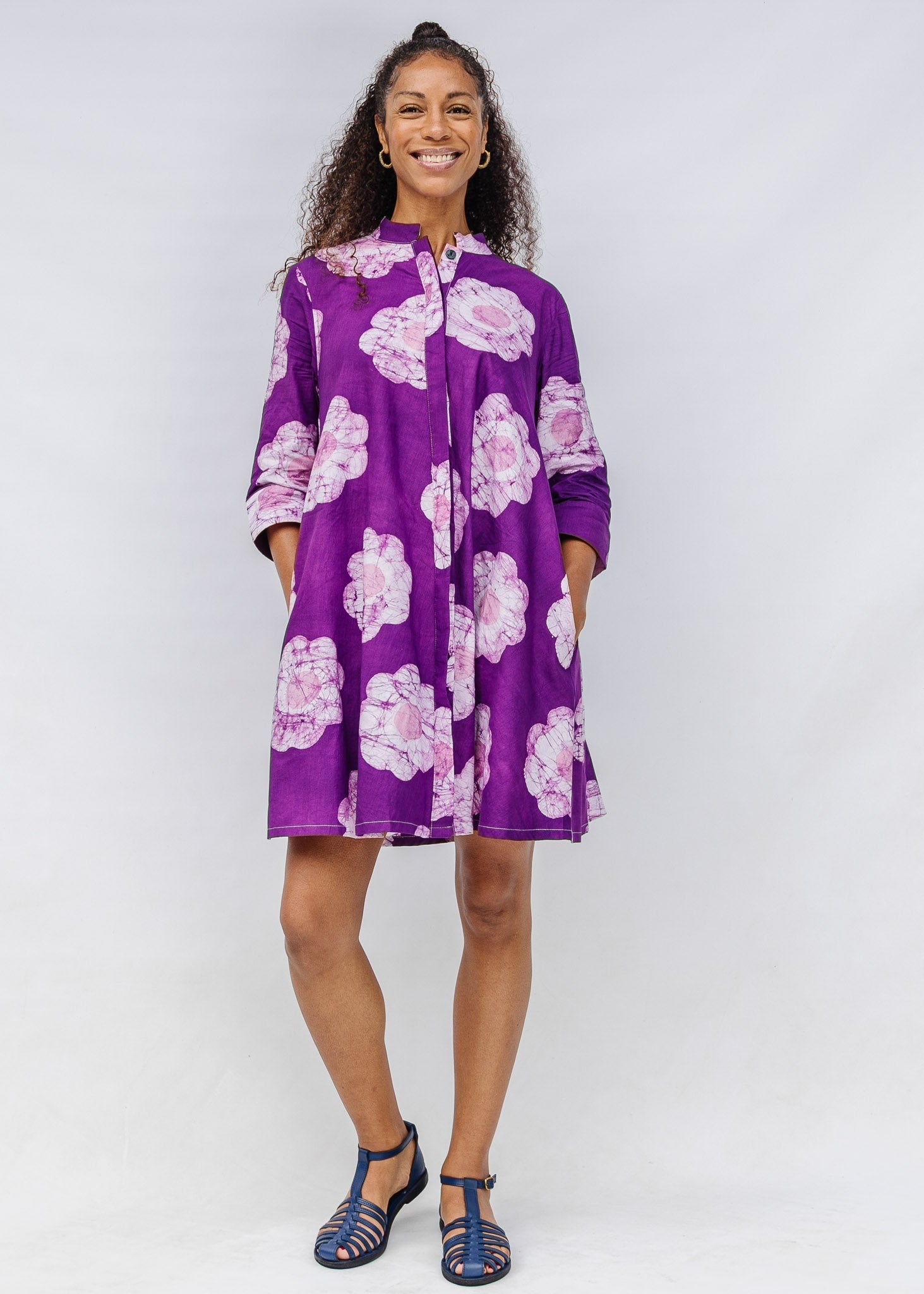 Woman wearing a purple floral dress against a white background