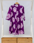 Purple dress with floral pattern on a wooden rack against a white background