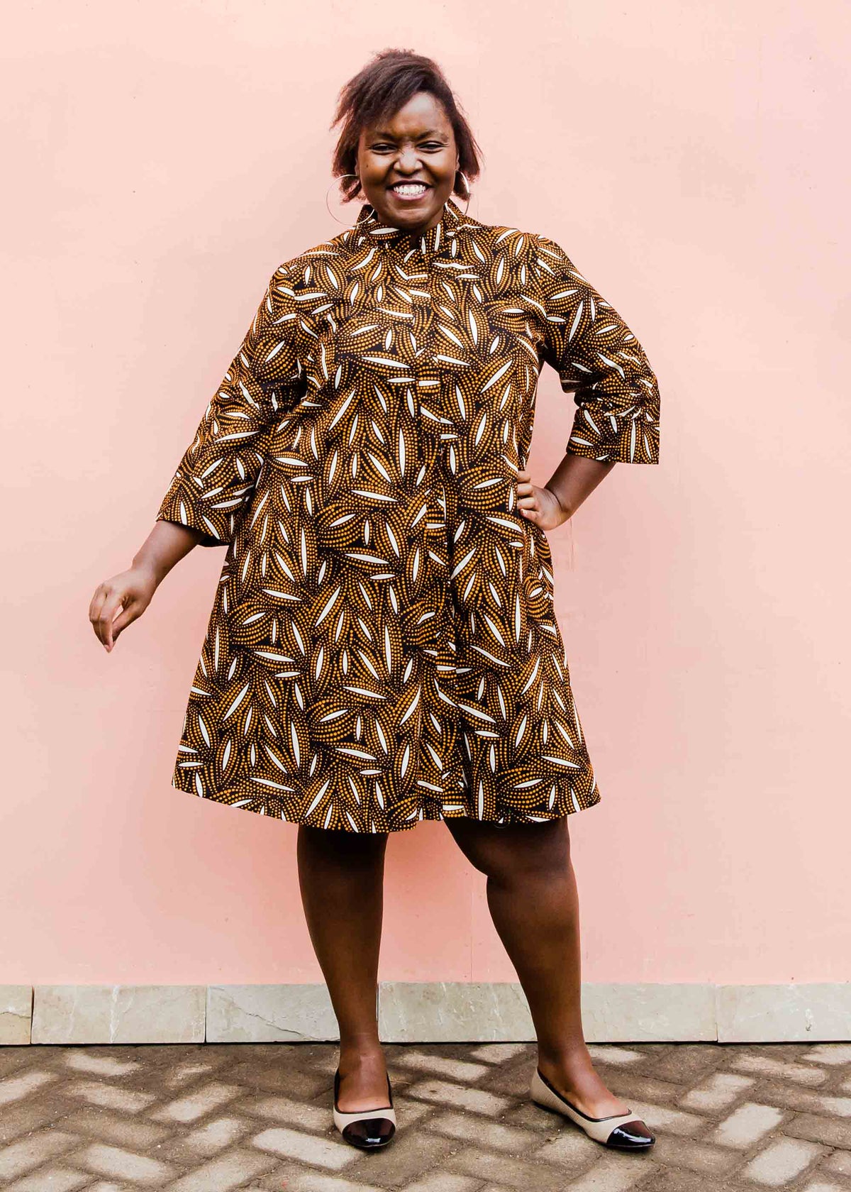 model wearing a brown, black and white seed design dress