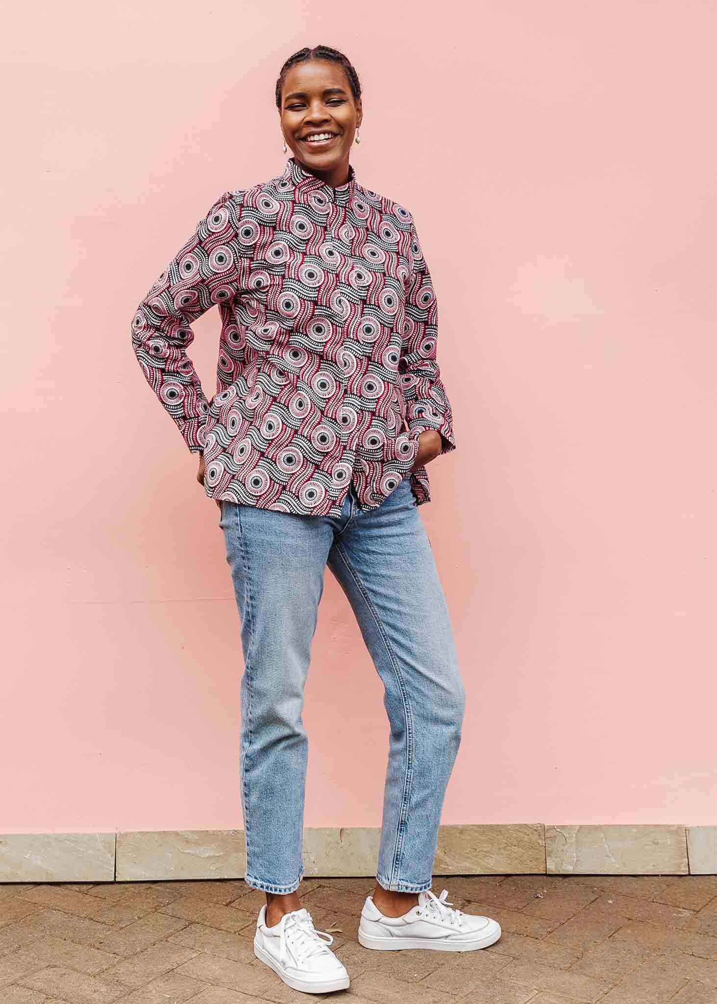 Model wearing long sleeve blouse with black, red, and white circles.